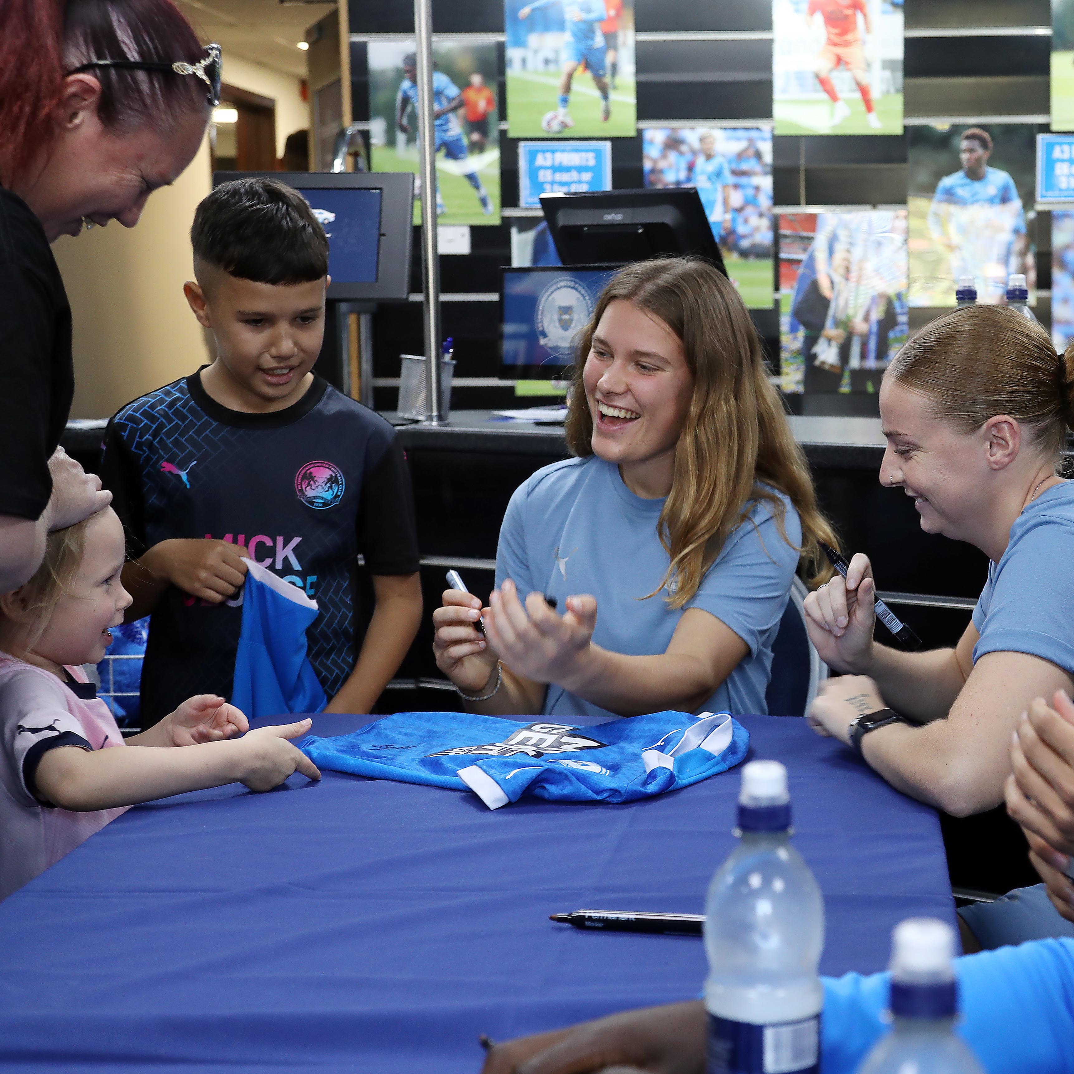 Posh Women players Hannah Dawbarn and Alex O'Neill interact with a young supporter